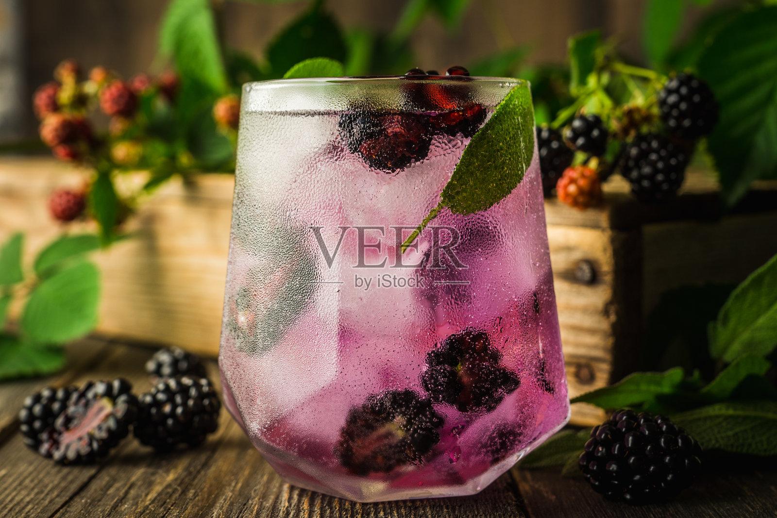 黑莓杜松子酒鸡尾酒,配有黑莓和树枝,置于乡村木质背景上照片摄影图片