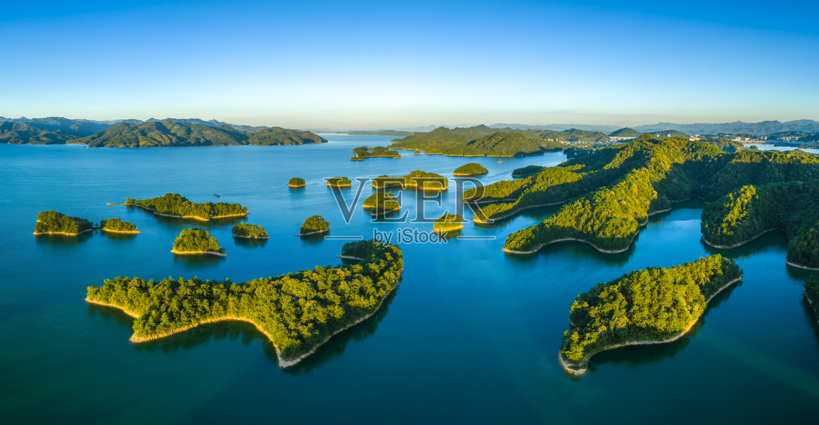 日出时分,壮丽湖泊、翠绿岛屿与群山构成的自然风光,鸟瞰视角照片摄影图片