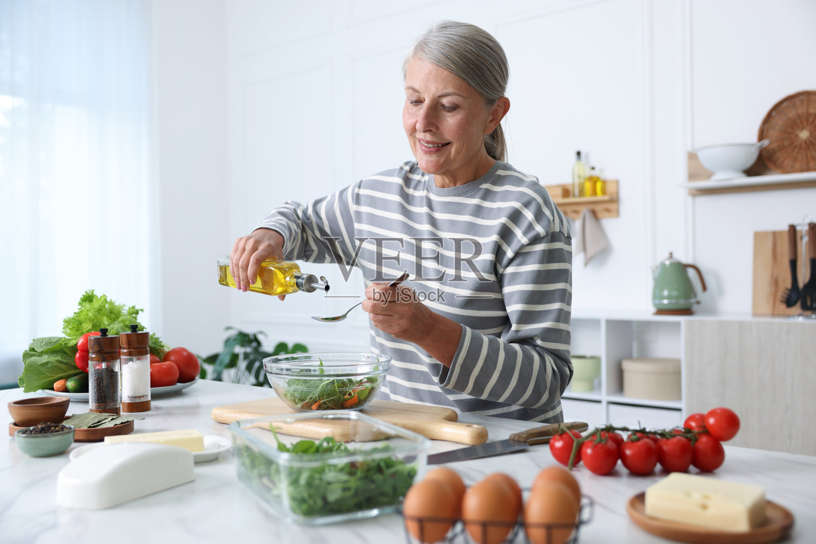 一位年长女性在厨房的白色大理石桌上烹饪沙拉照片摄影图片
