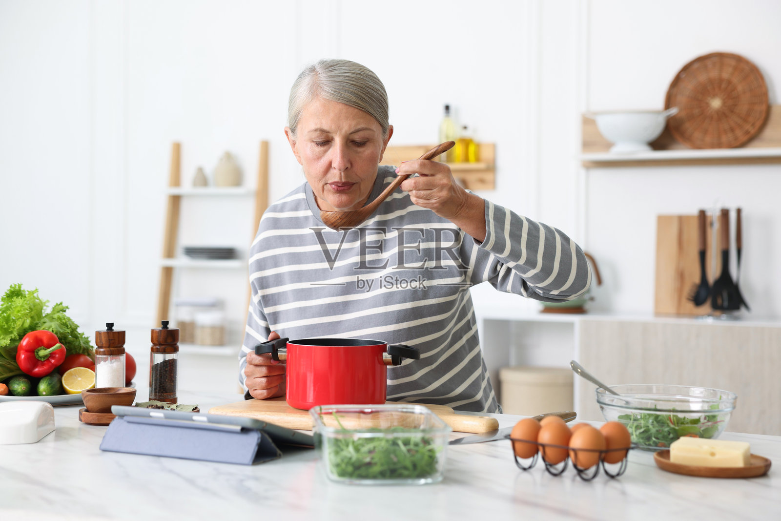 一位年长的女性在厨房的白色大理石桌上烹饪照片摄影图片