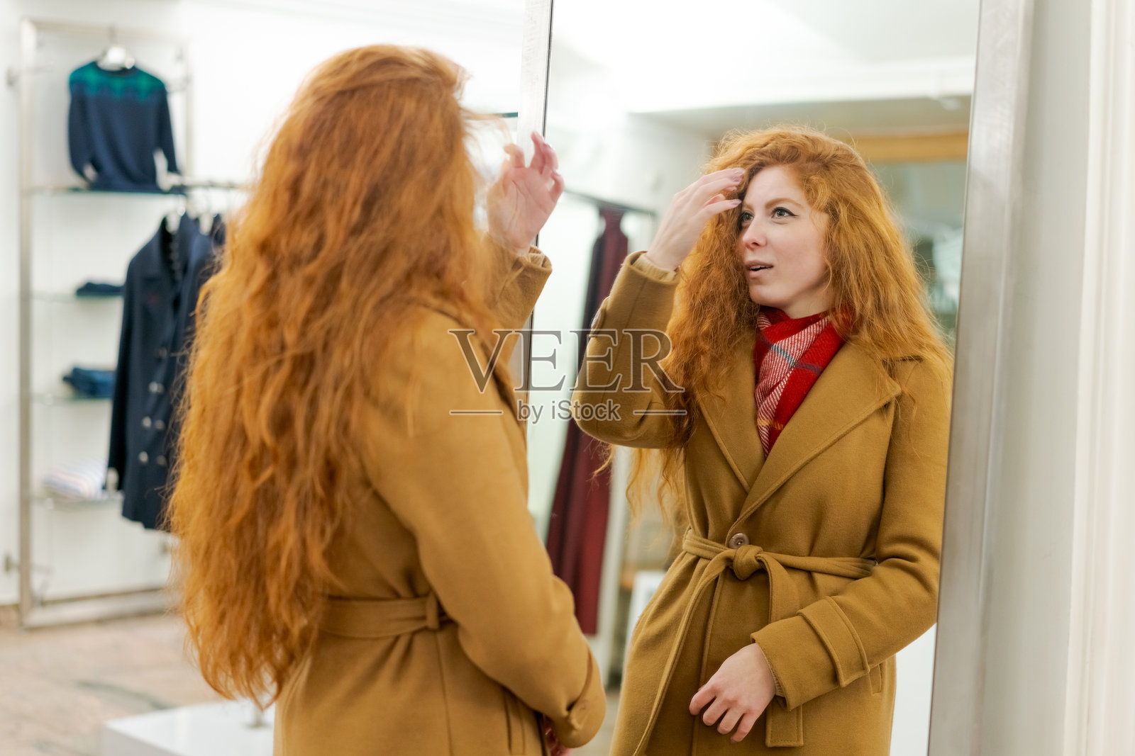 一位红发女子正在镜子中审视自己照片摄影图片