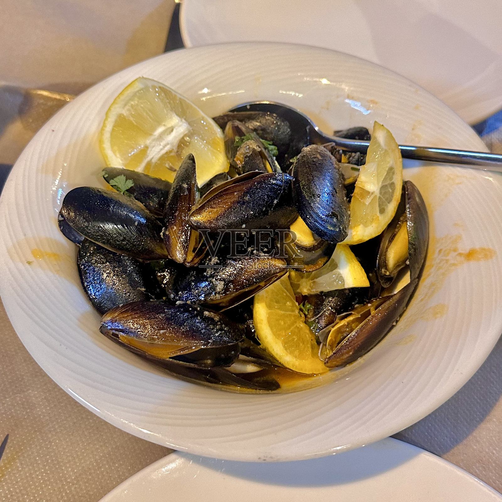 贻贝海鲜地中海贝类碗,配有柠檬、柑橘、大蒜、欧芹、白葡萄酒、黄油酱汁,蒸煮烹制,适合晚餐、午餐、开胃菜、小吃,意式法式小酒馆风格,新鲜、美味、芳香、多汁、光泽照片摄影图片