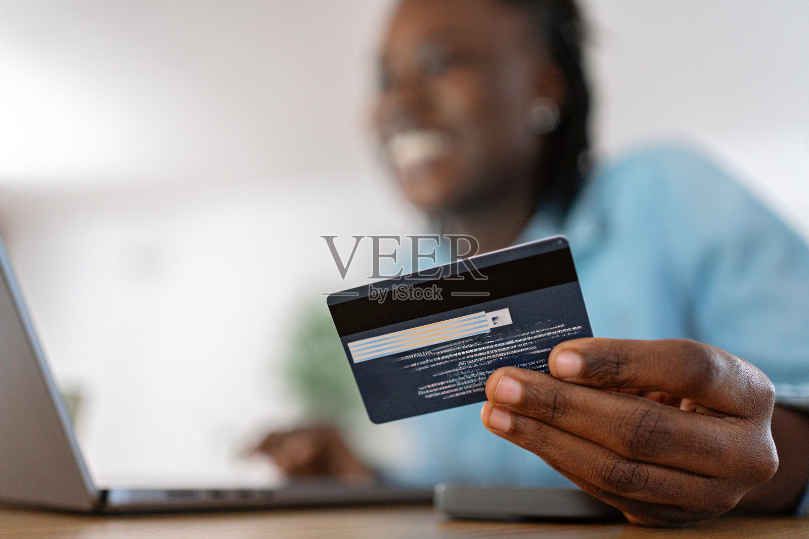 一位快乐的年轻黑人女性在家中笔记本电脑上使用信用卡进行在线购物照片摄影图片