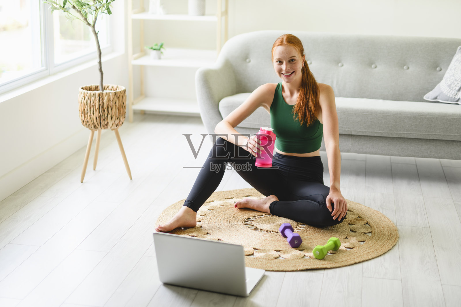 身材匀称的女性在客厅做瑜伽平板支撑,并通过笔记本电脑观看在线教程进行训练照片摄影图片