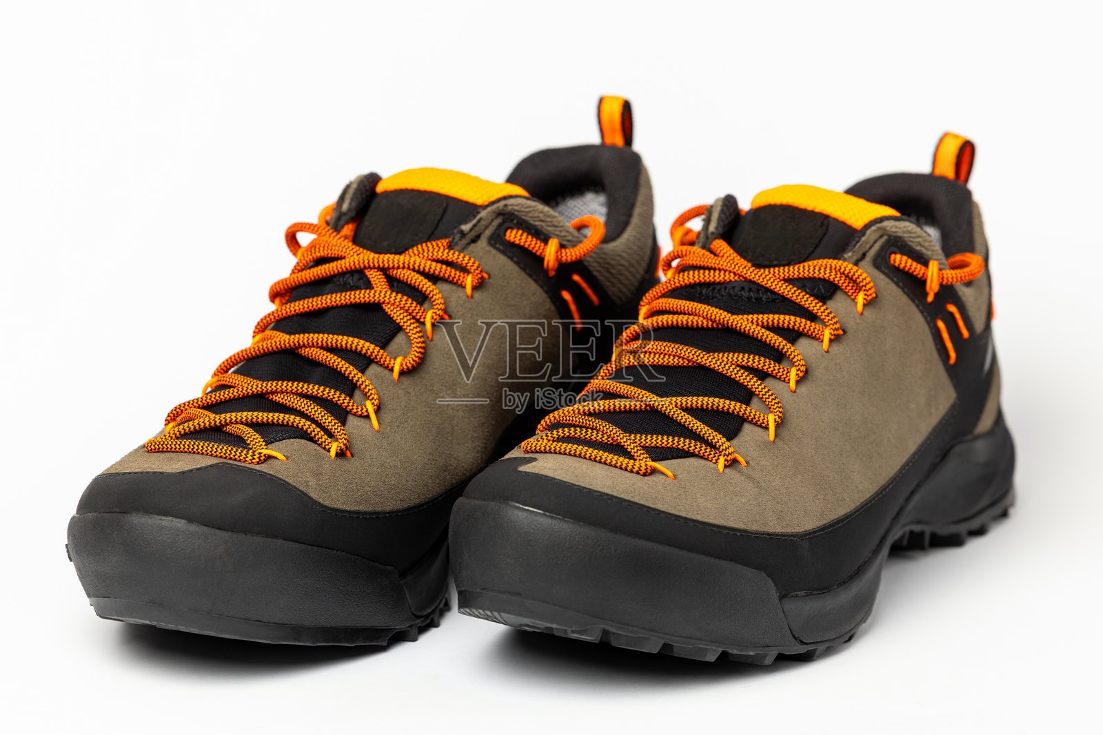 米色徒步靴,配有彩色的橙色鞋带,置于白色背景上。照片摄影图片