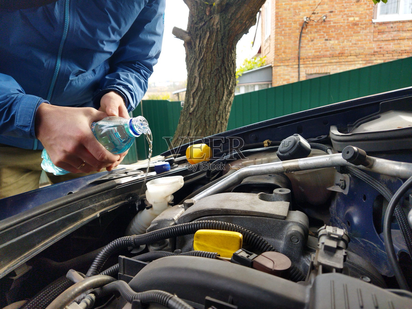 男人向汽车发动机冷却液储液罐加注冷却液照片摄影图片