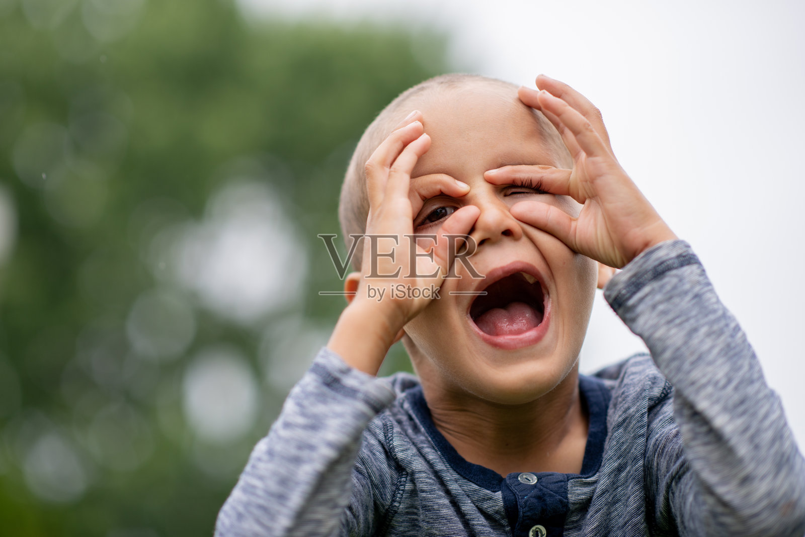 孩子在户外尖叫,双手捂脸,尽显兴奋、惊喜和玩闹的活力照片摄影图片