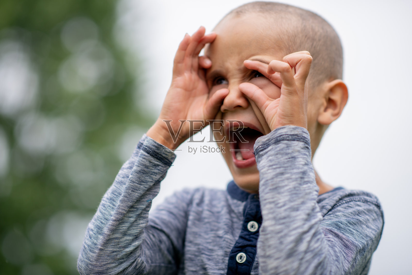 小男孩在户外,双手靠近脸颊,表情痛苦地大声哭泣照片摄影图片