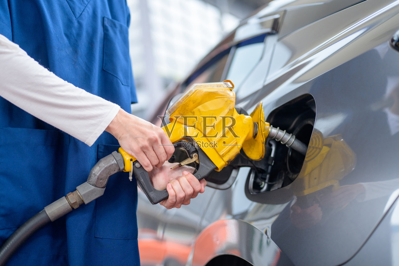 一名女子正在用油枪给汽车加油照片摄影图片