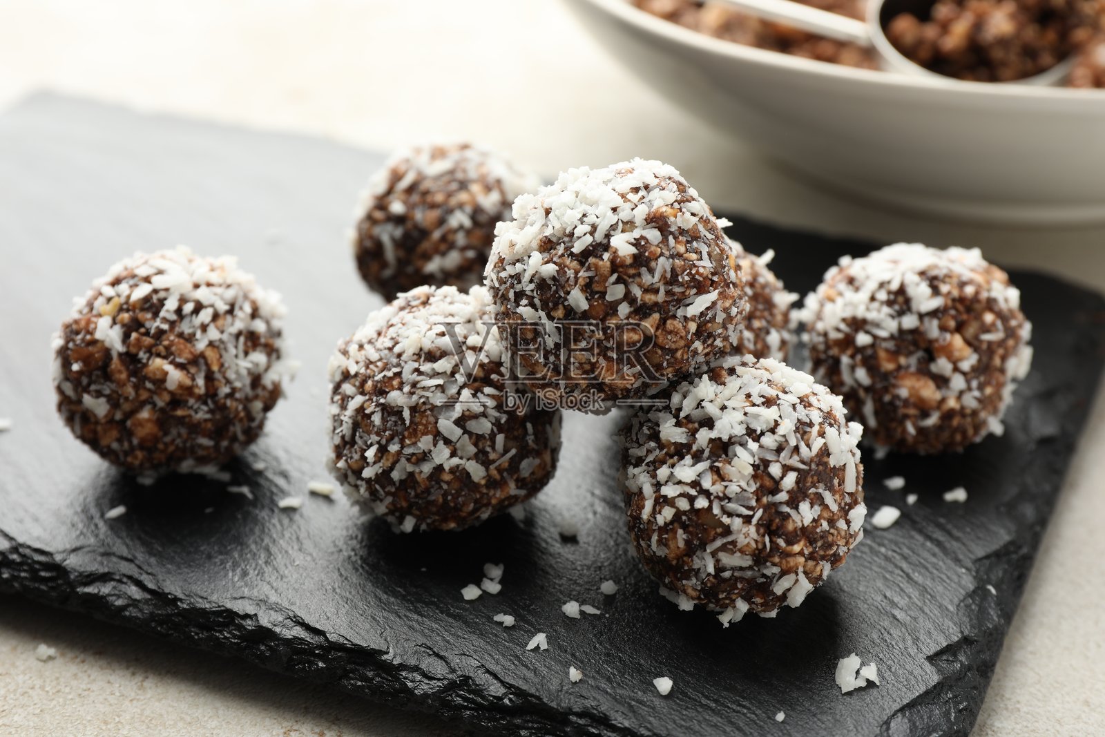 浅色桌子上的美味巧克力糖果,配有坚果和椰子片,特写照片摄影图片
