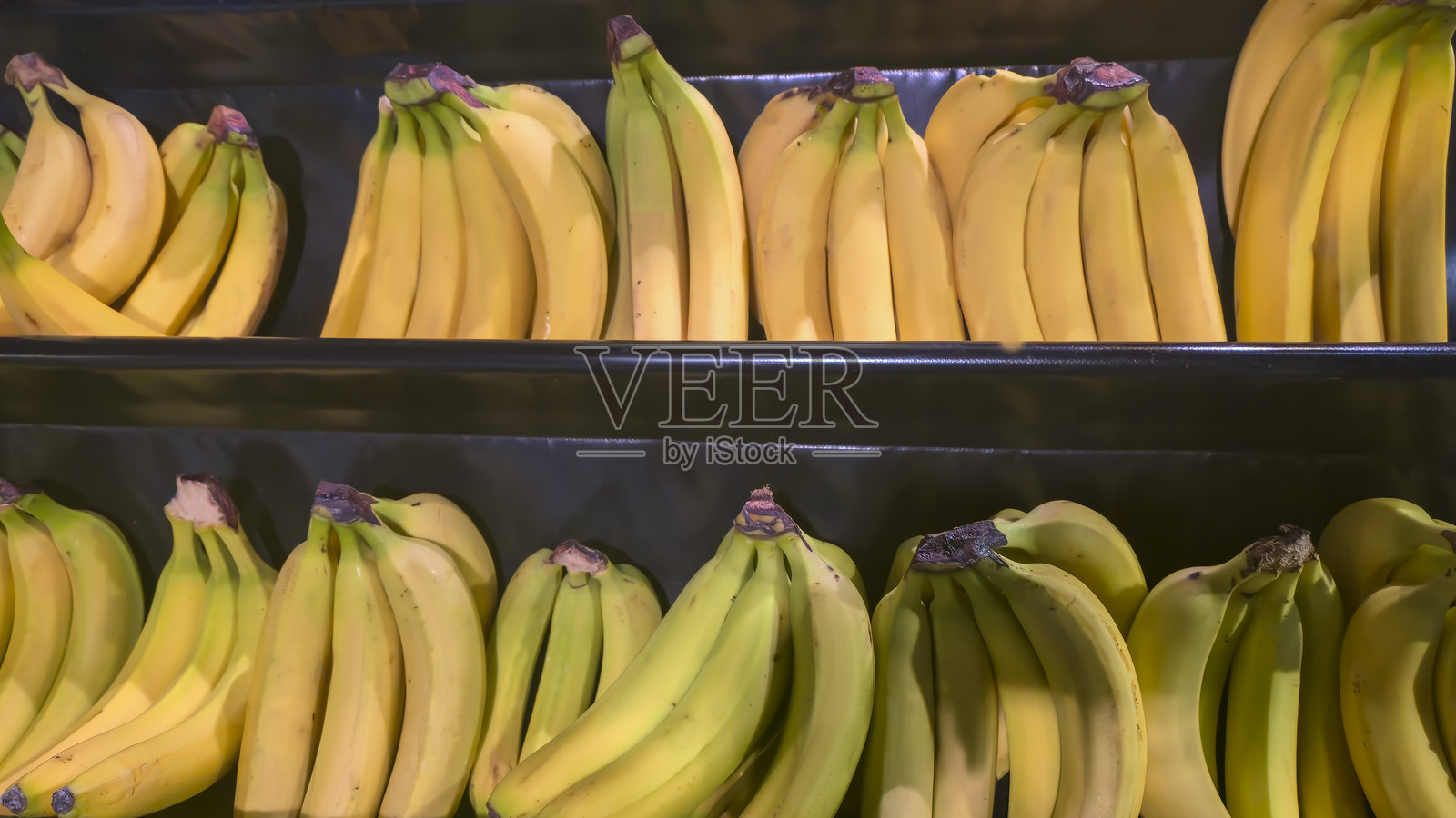 超市货架上成堆的香蕉装在大箱子里,准备出售。照片摄影图片