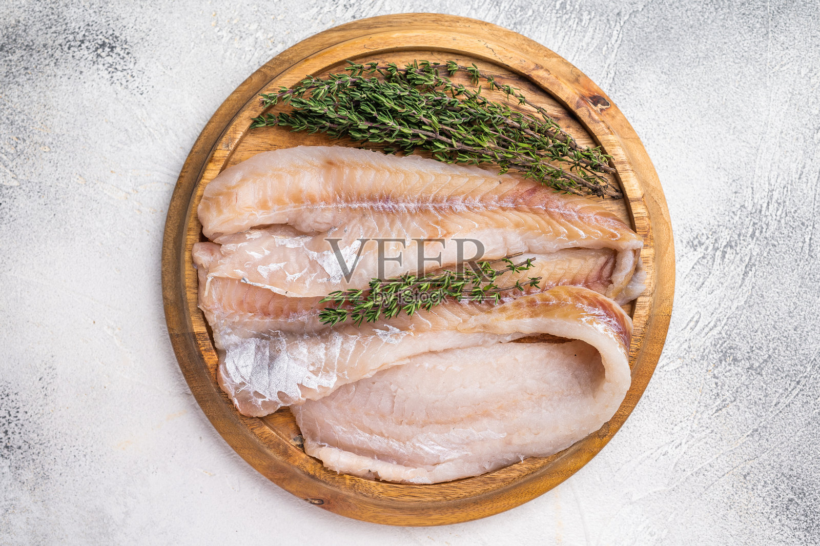 新鲜的生鳕鱼柳,白鱼肉放在木板上,配有香草。白色背景。俯视图照片摄影图片