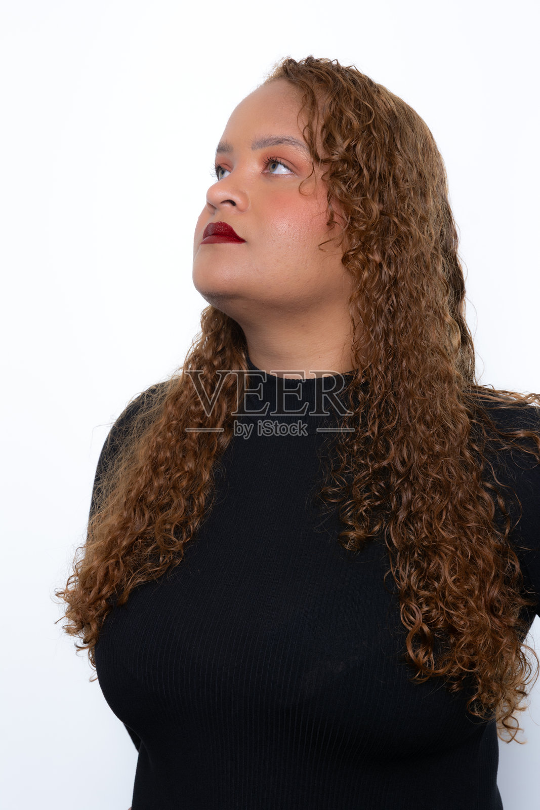 身穿黑衬衫、卷发、仰望的漂亮女子,背景为白色。摄影模特照片摄影图片