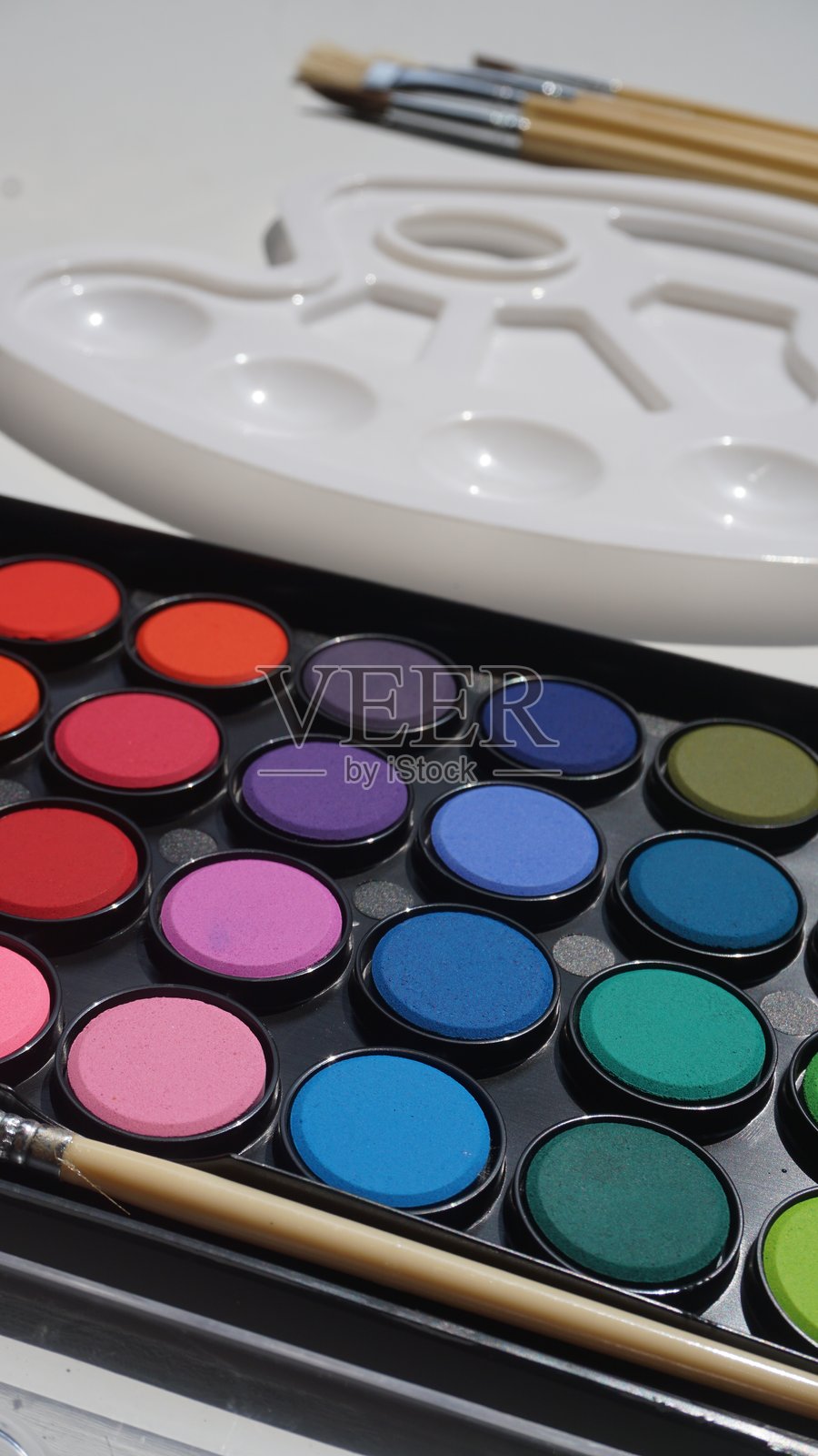 白色背景上的彩色眼影盘和化妆刷照片摄影图片