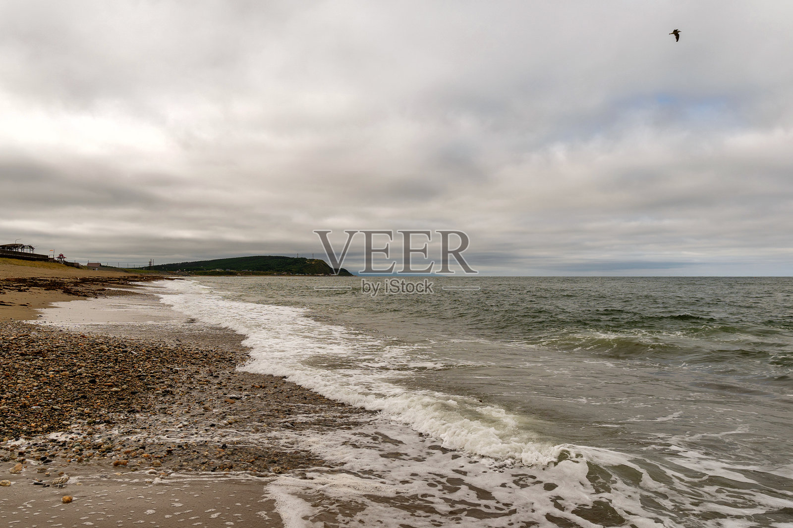 阴云密布的天空下,岩石海岸与远处的岬角照片摄影图片