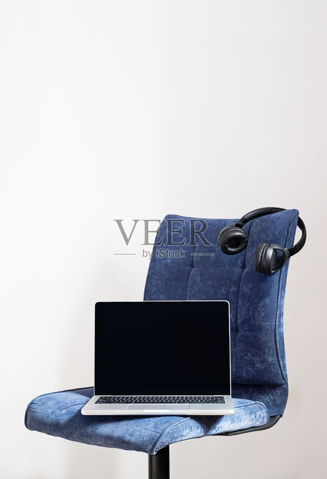 笔记本电脑和无线耳机放在行政办公椅上。现代远程办公照片摄影图片