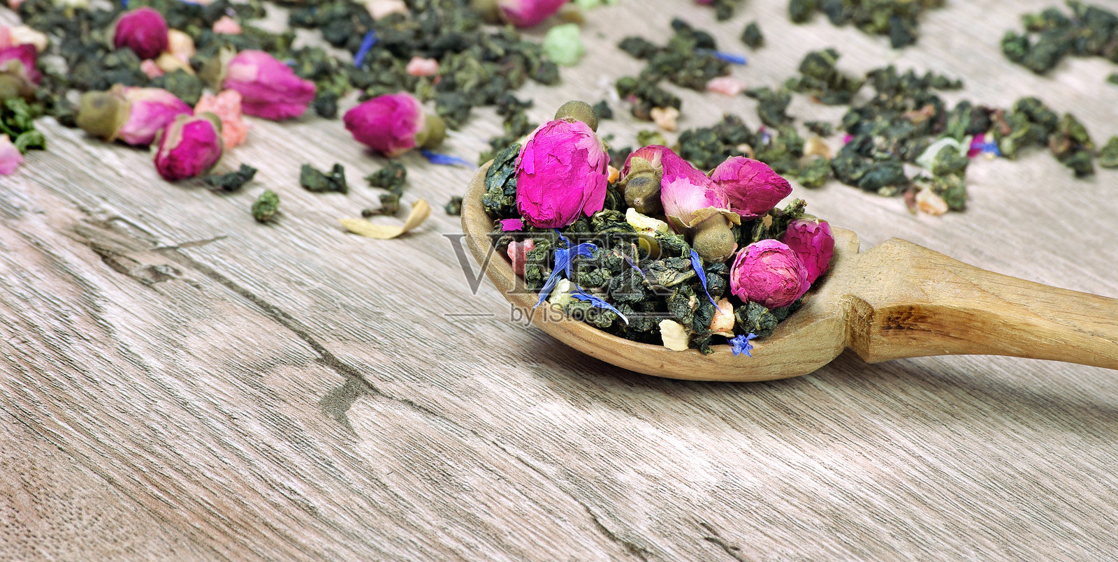 绿茶。木勺里的绿茶和花。绿茶、花和水果块。混合茶照片摄影图片