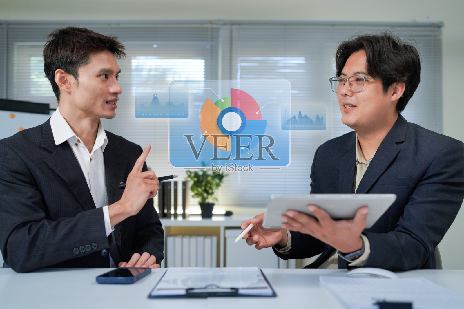 两位商务人士正在使用平板电脑和文件讨论业务增长,非常适合商务演示或报告。照片摄影图片