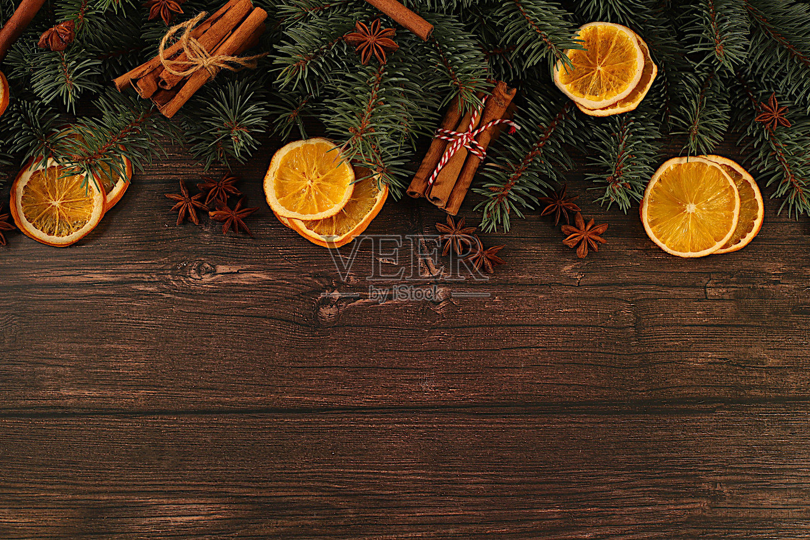 新鲜的冷杉枝,上面有干橙子、八角、肉桂和松果,放在木桌上。圣诞节构图和新年2026概念,新年设计和产品展示模型,冬季屏幕横幅。照片摄影图片