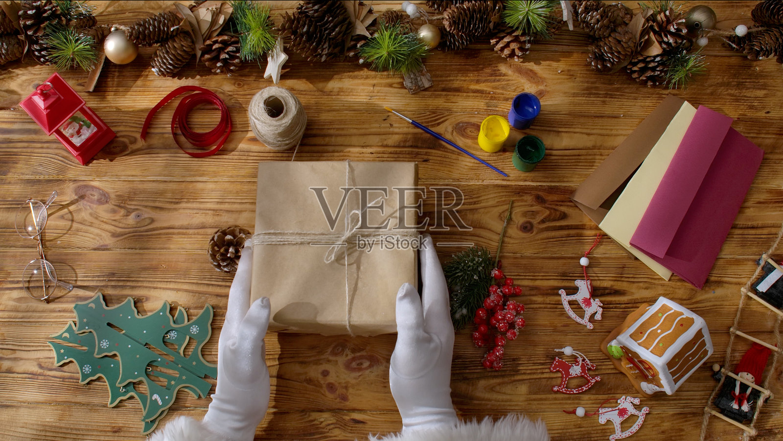 圣诞老人正在木桌上准备圣诞礼物。照片摄影图片