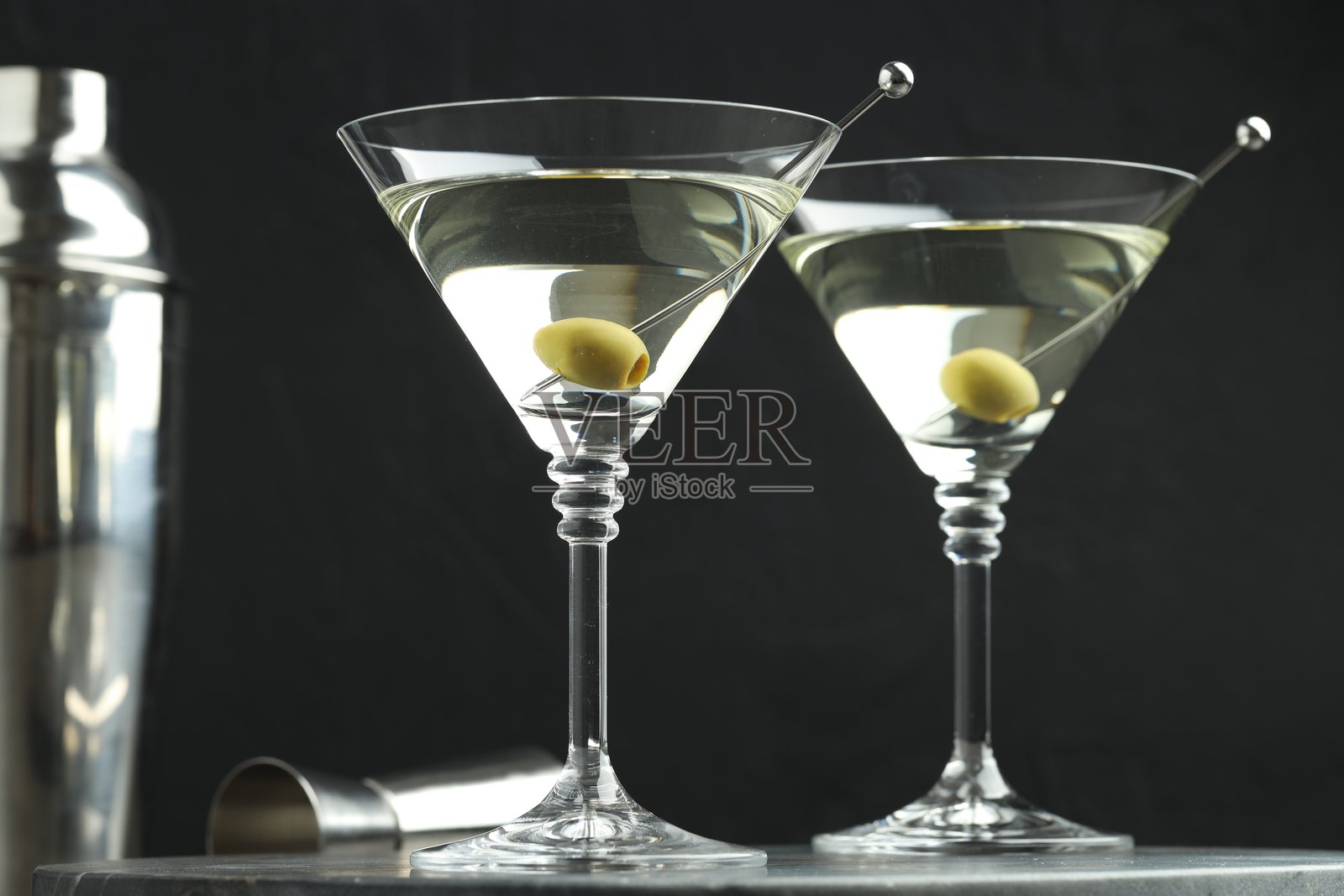 特写:黑色背景下的灰色桌子上放着橄榄的马提尼鸡尾酒杯照片摄影图片