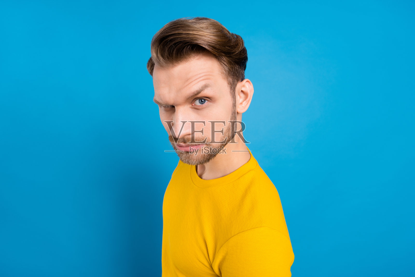 年轻男子侧面照,鬼鬼祟祟的表情,间谍,不确定,孤立,蓝色背景照片摄影图片