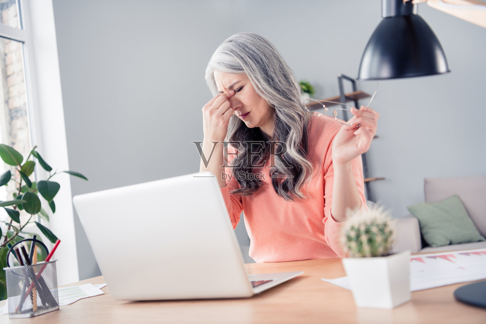 一名过劳的、生病的有魅力的女性在室内公寓的家中,努力工作,感觉不适照片摄影图片