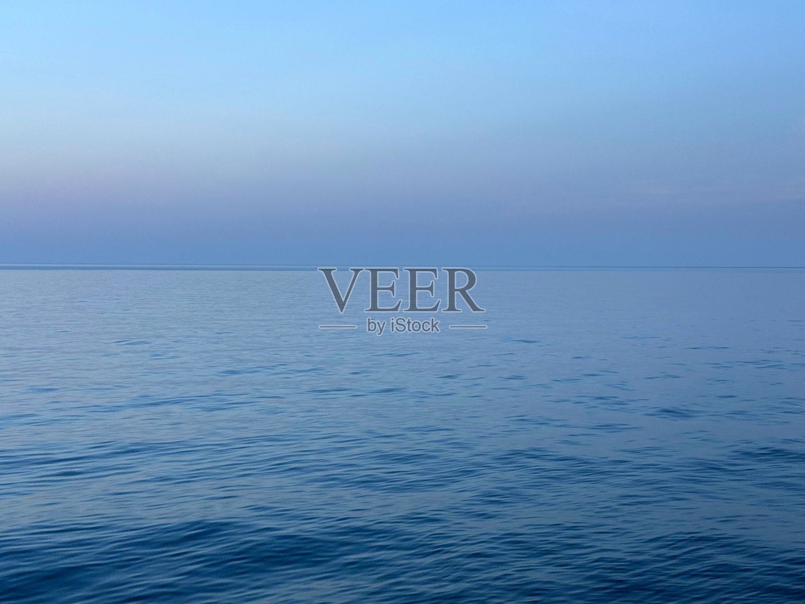 傍晚时分,平静的海面和蓝色的天空。照片摄影图片