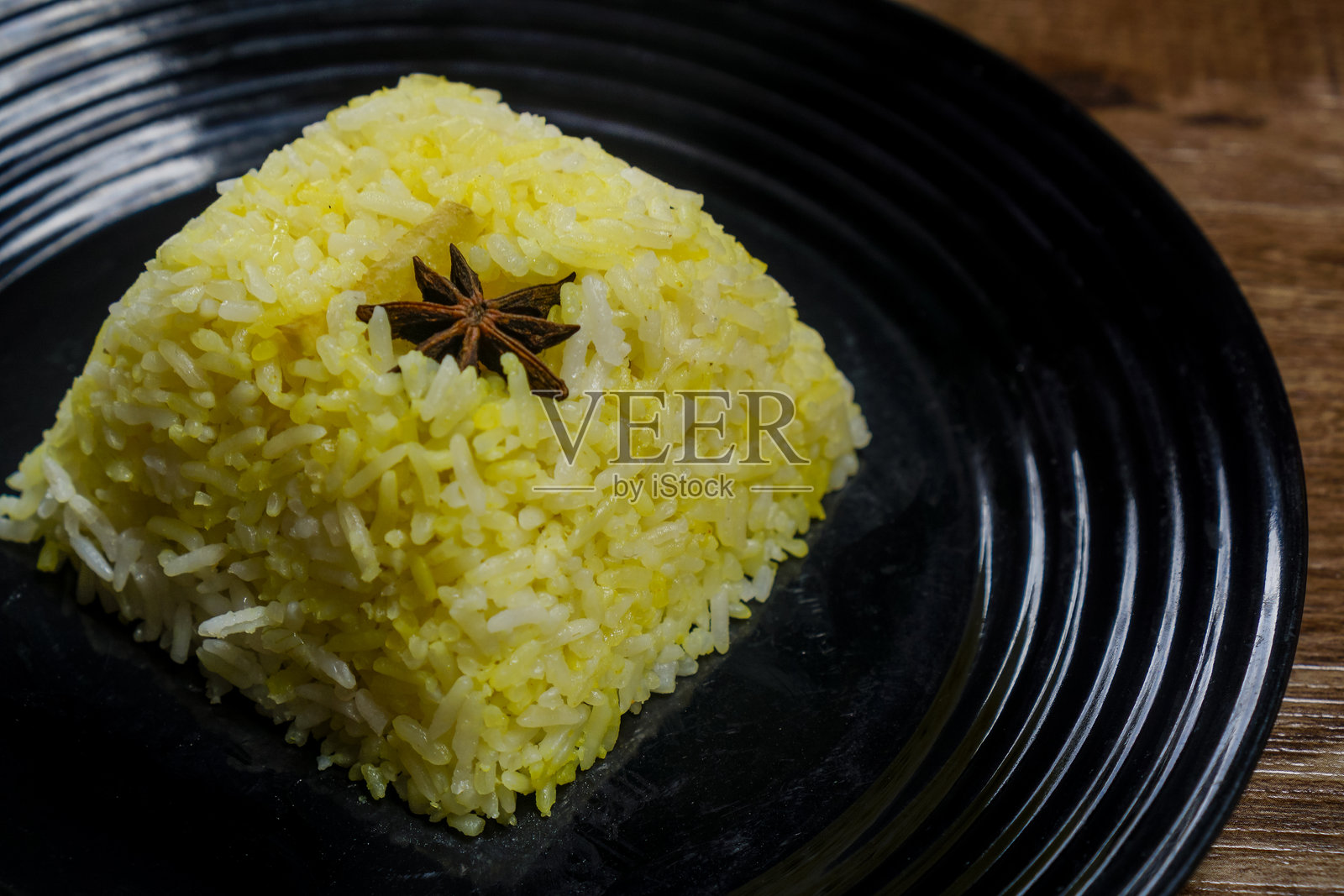香料饭(Nasi Minyak)或黄油饭盛在盘子里,用八角装饰,孤立在木质背景上。照片摄影图片