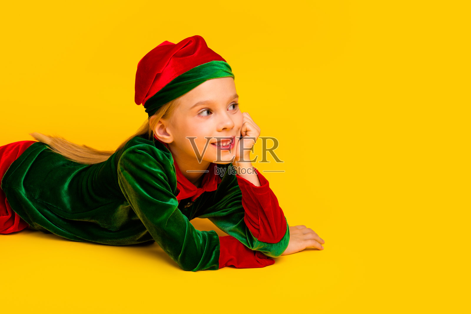 身着缤纷精灵服饰的快乐孩子在节日圣诞季,于鲜亮的黄色背景前摆姿势。照片摄影图片