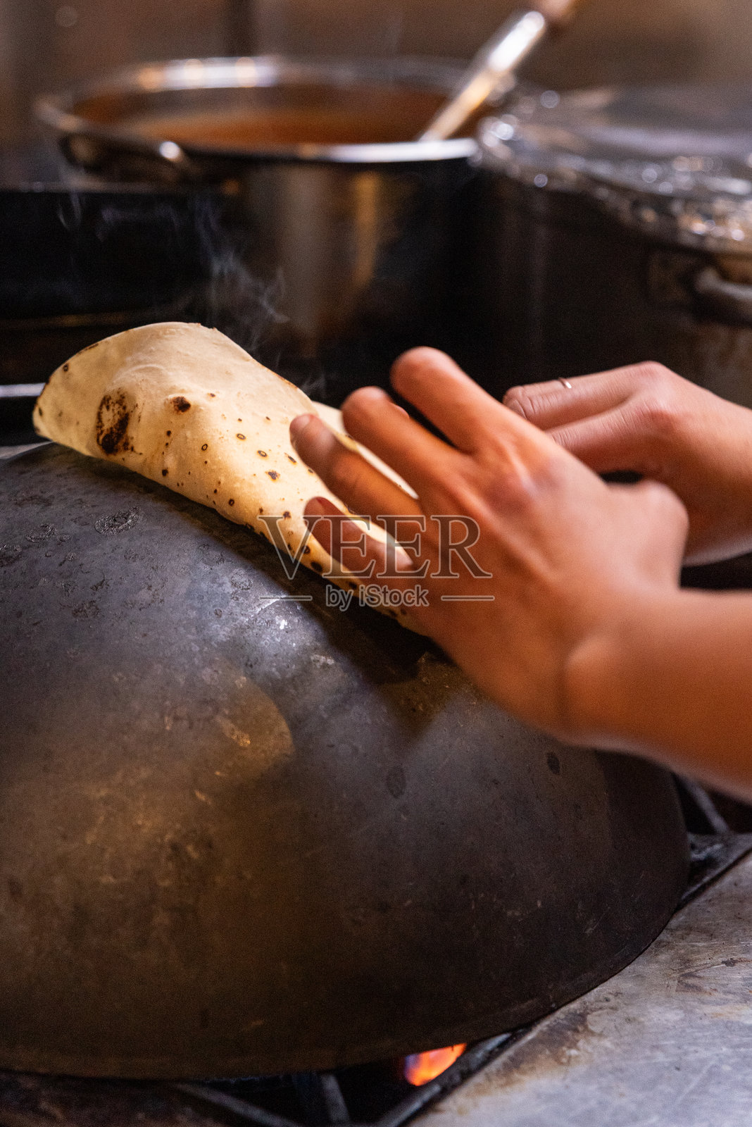 餐厅厨房里,厨师在炉灶上烹饪印度薄饼照片摄影图片