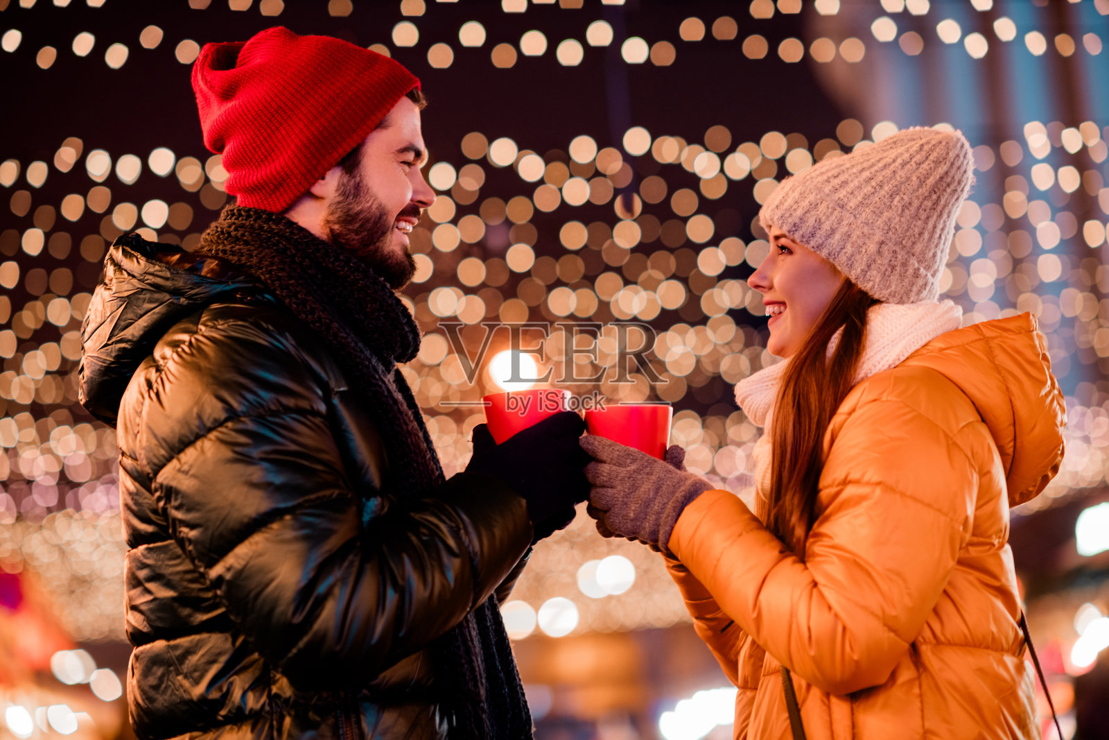 在冬日城市集市,一对快乐的夫妇在节日灯光下分享热饮,在欢乐的节日夜晚庆祝爱情与团聚。照片摄影图片