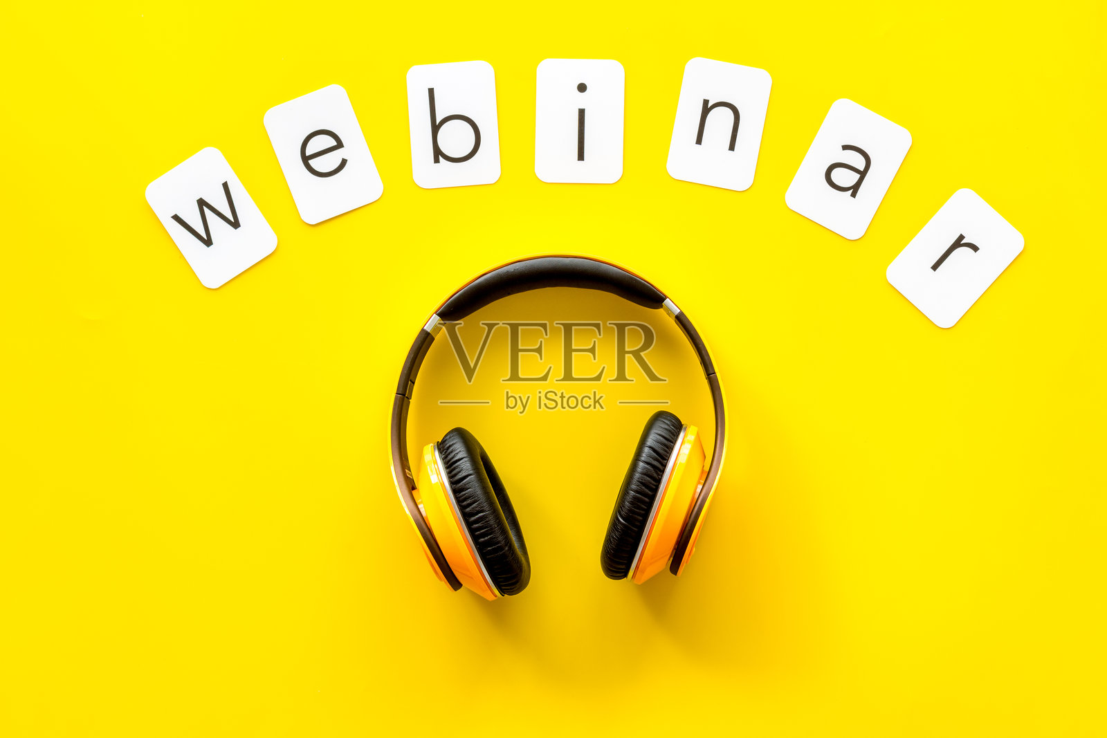 纸卡上的“网络研讨会”字样。黄桌工作区上的耳机,俯视照片摄影图片