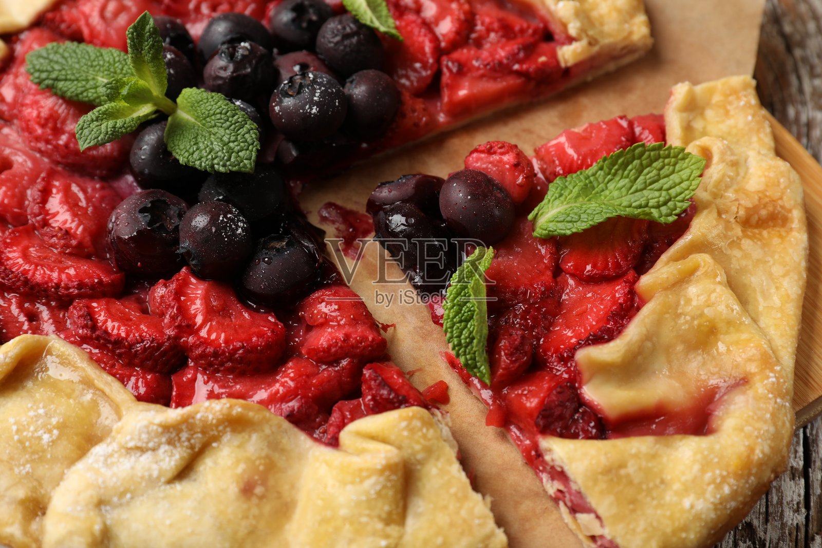 桌上放着美味的草莓、蓝莓和薄荷馅饼,特写照片摄影图片