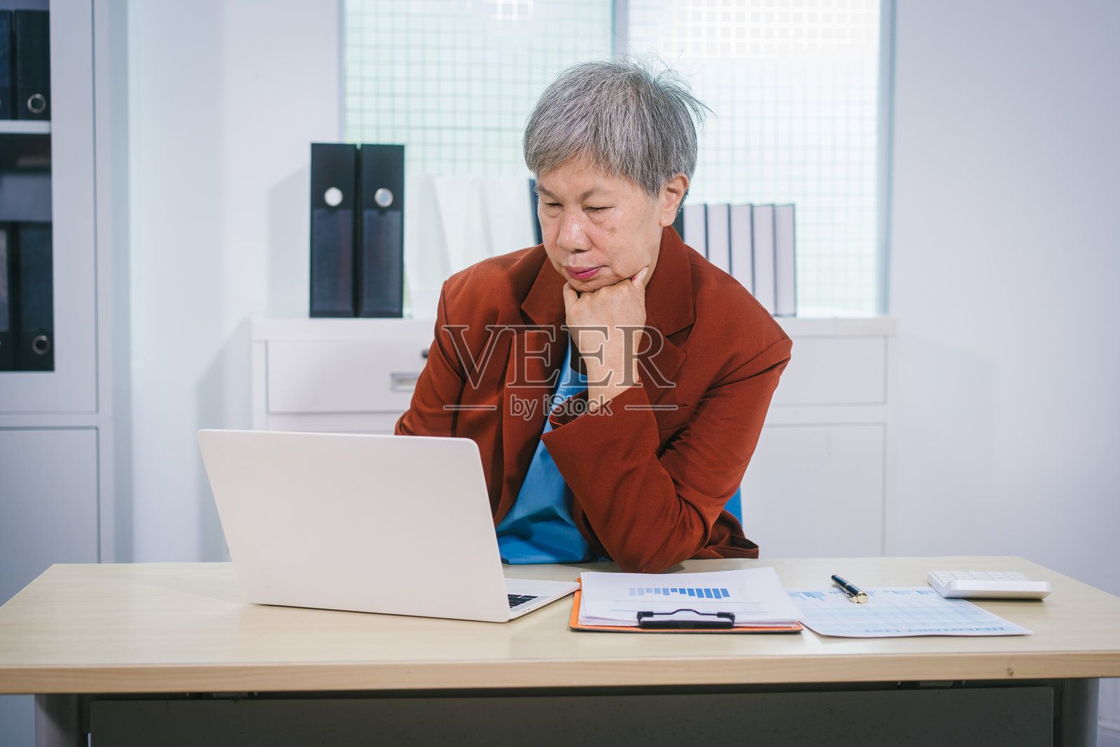 经验丰富的亚裔女性,拥有专业的办公室工作经验,专注于审阅财务报告和投资文件,体现了她在商业、金融和投资策略方面的专业知识照片摄影图片