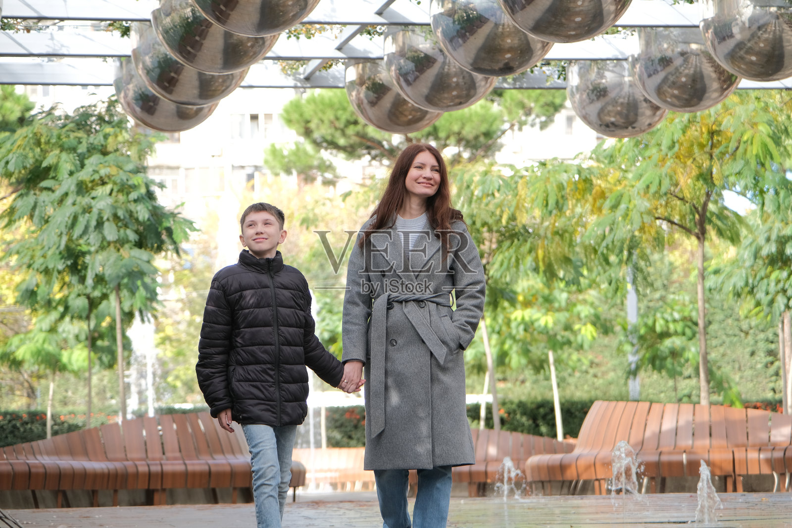 母亲与儿子在公园里手牵手散步照片摄影图片