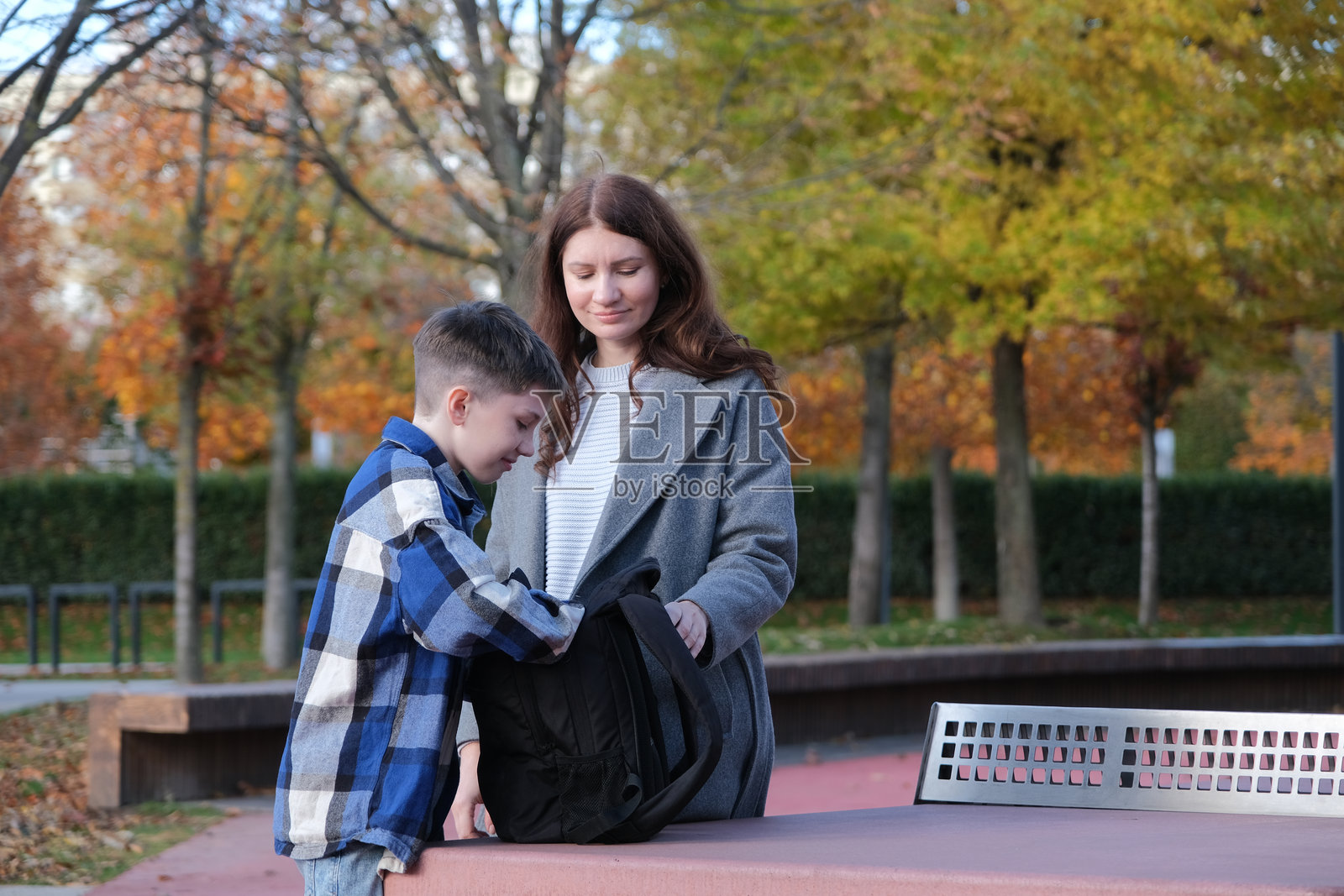 母子俩在公园里站着,在背包里翻找物品照片摄影图片