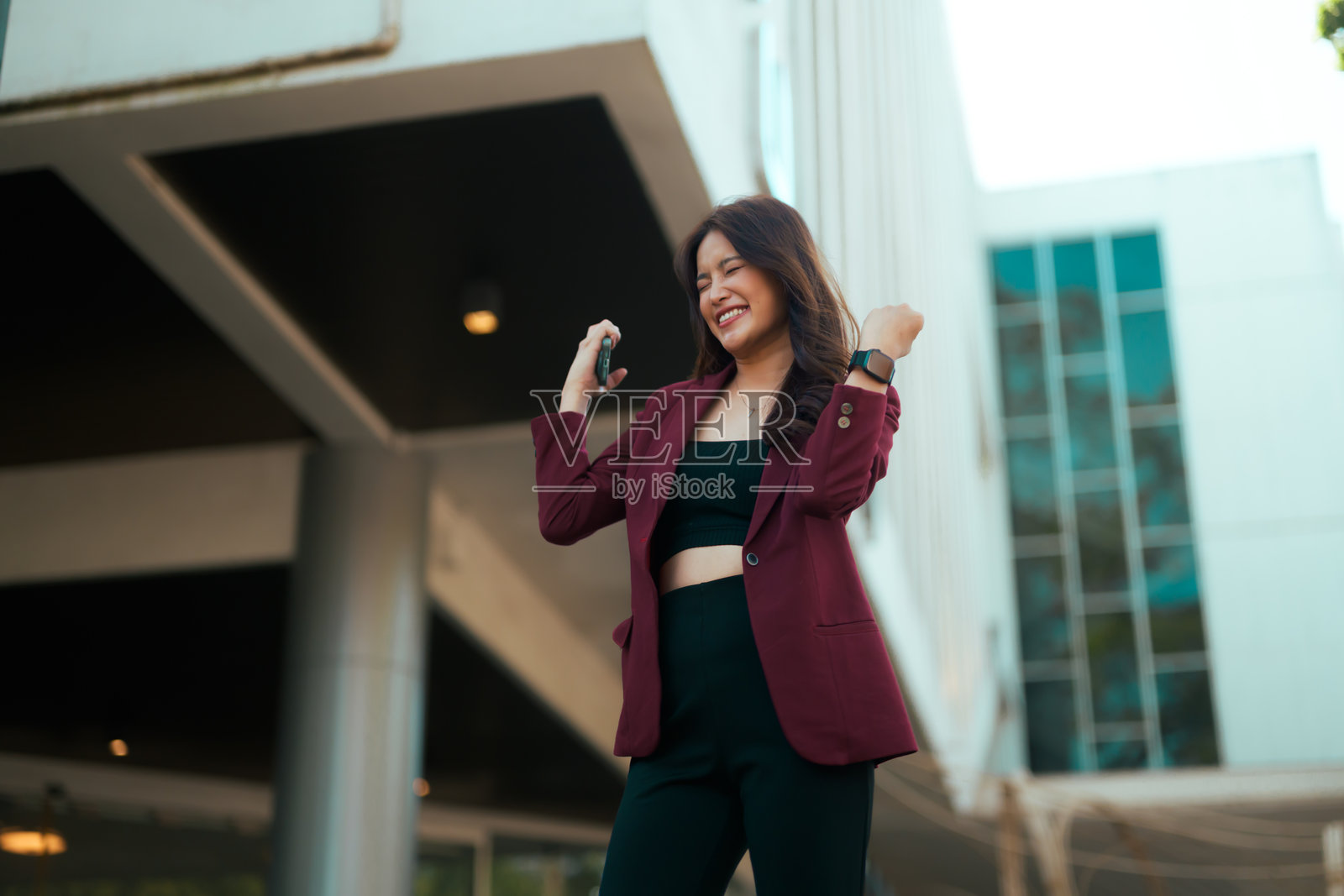 年轻职业女性庆祝事业成就,高举握拳的手臂,感到兴奋和快乐照片摄影图片