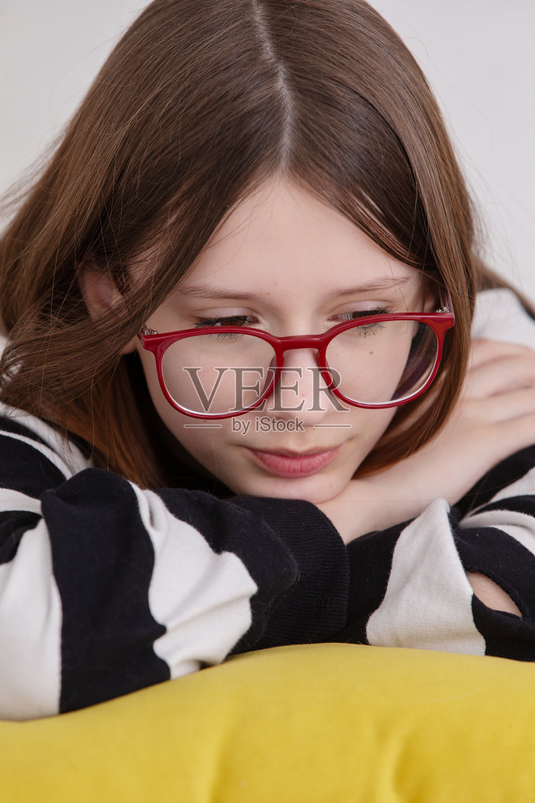 年轻女孩穿着条纹毛衣,双手托腮,在家中舒适的环境里陷入沉思照片摄影图片