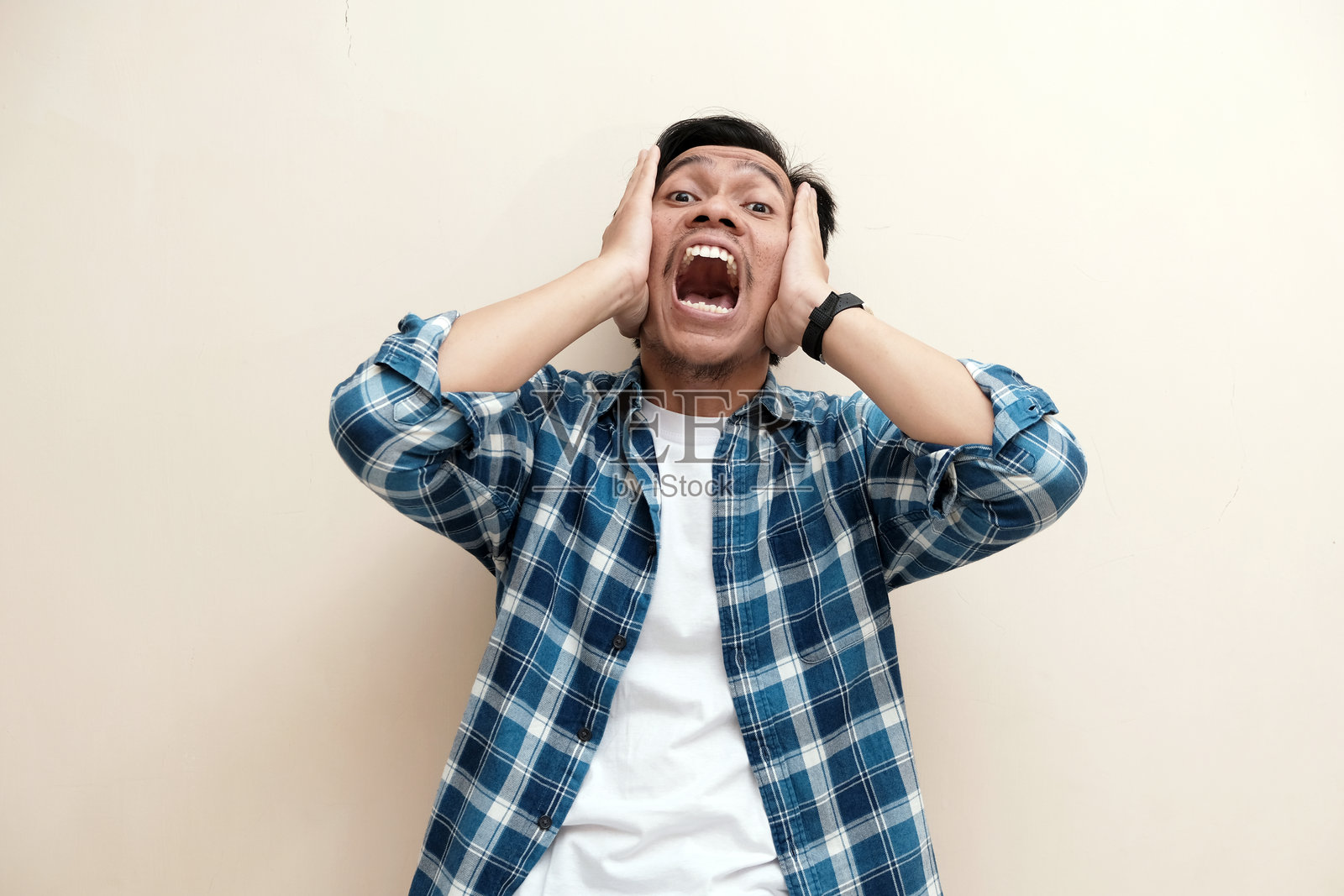 东南亚男子穿着格子衬衫,表情震惊照片摄影图片