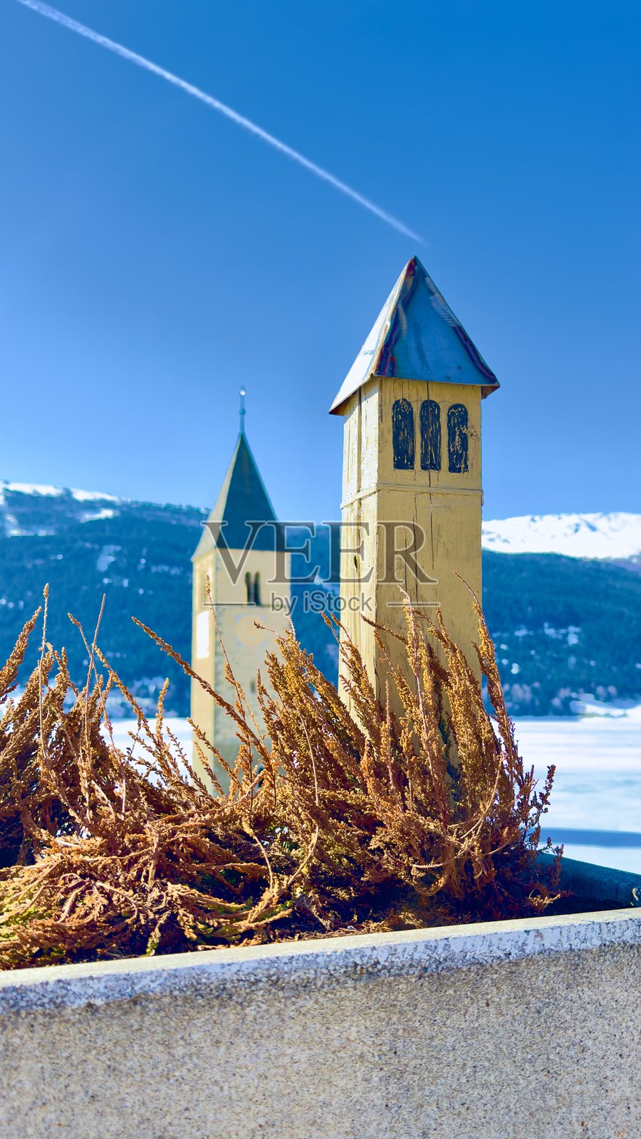 意大利南蒂罗尔地区,雷西亚湖(Lake Resia)冰封湖面上升起的历史沉没教堂塔楼照片摄影图片