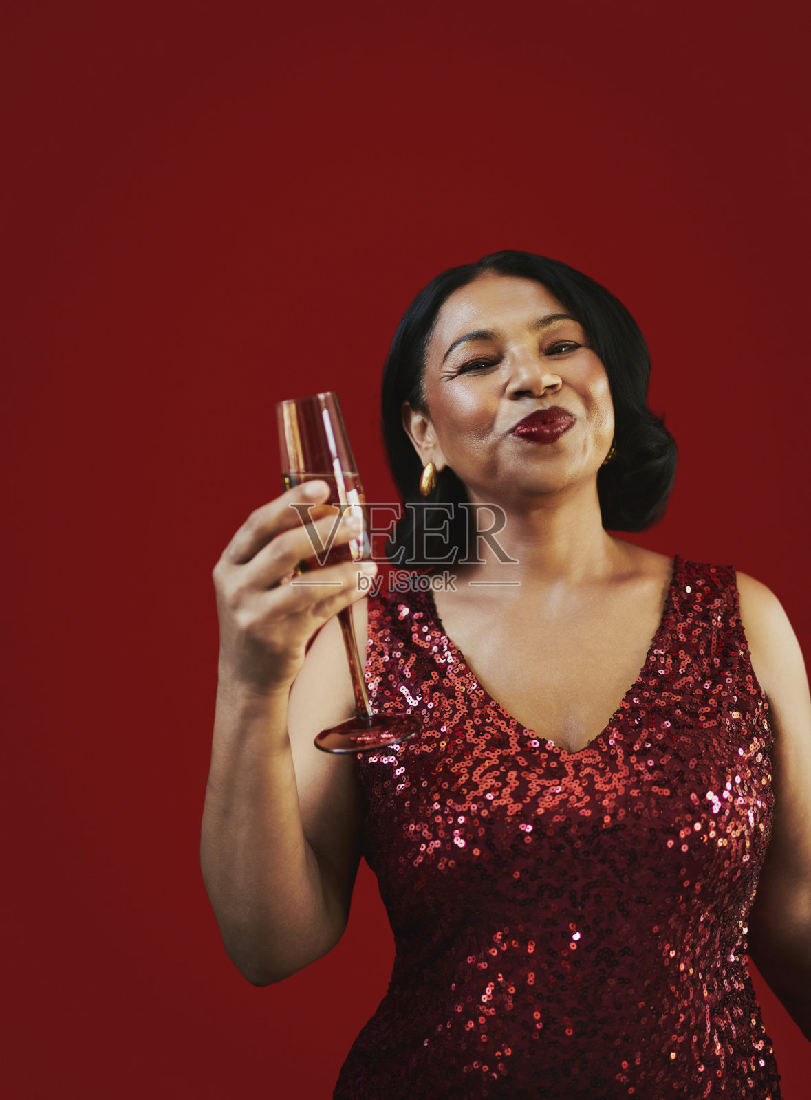 身穿红色亮片连衣裙的女士正在举杯庆祝照片摄影图片