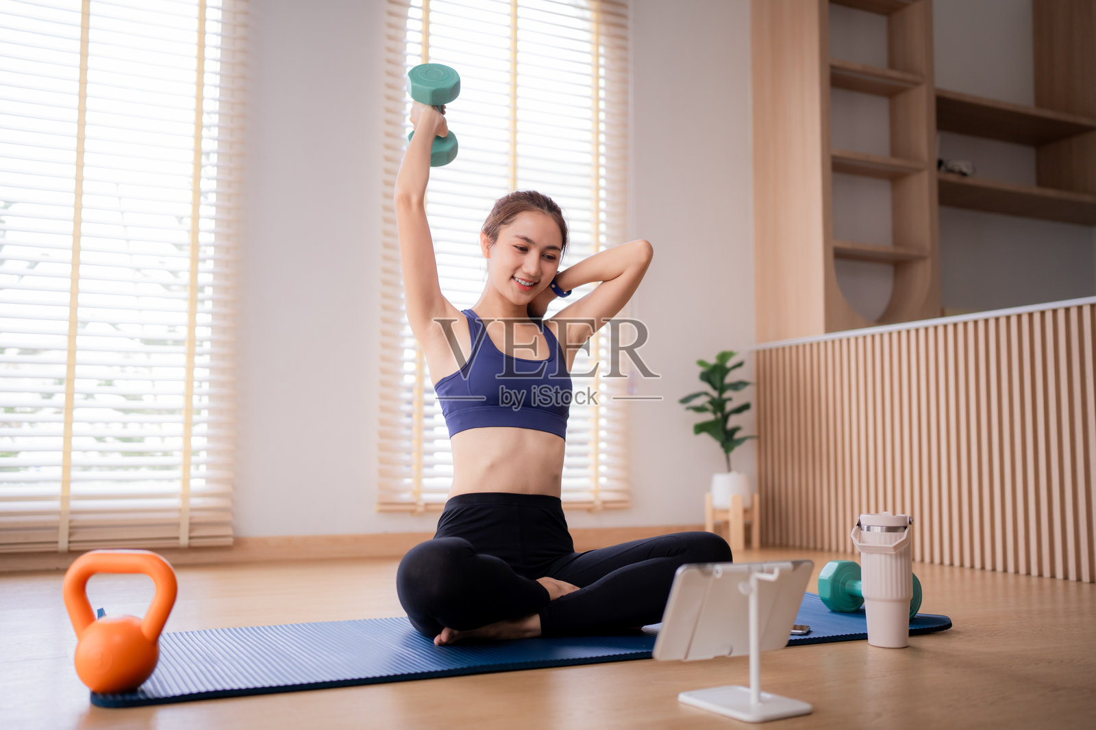 亚洲成年女性在家跟着在线健身课程训练哑铃,健康生活方式,养生,室内锻炼,力量训练照片摄影图片