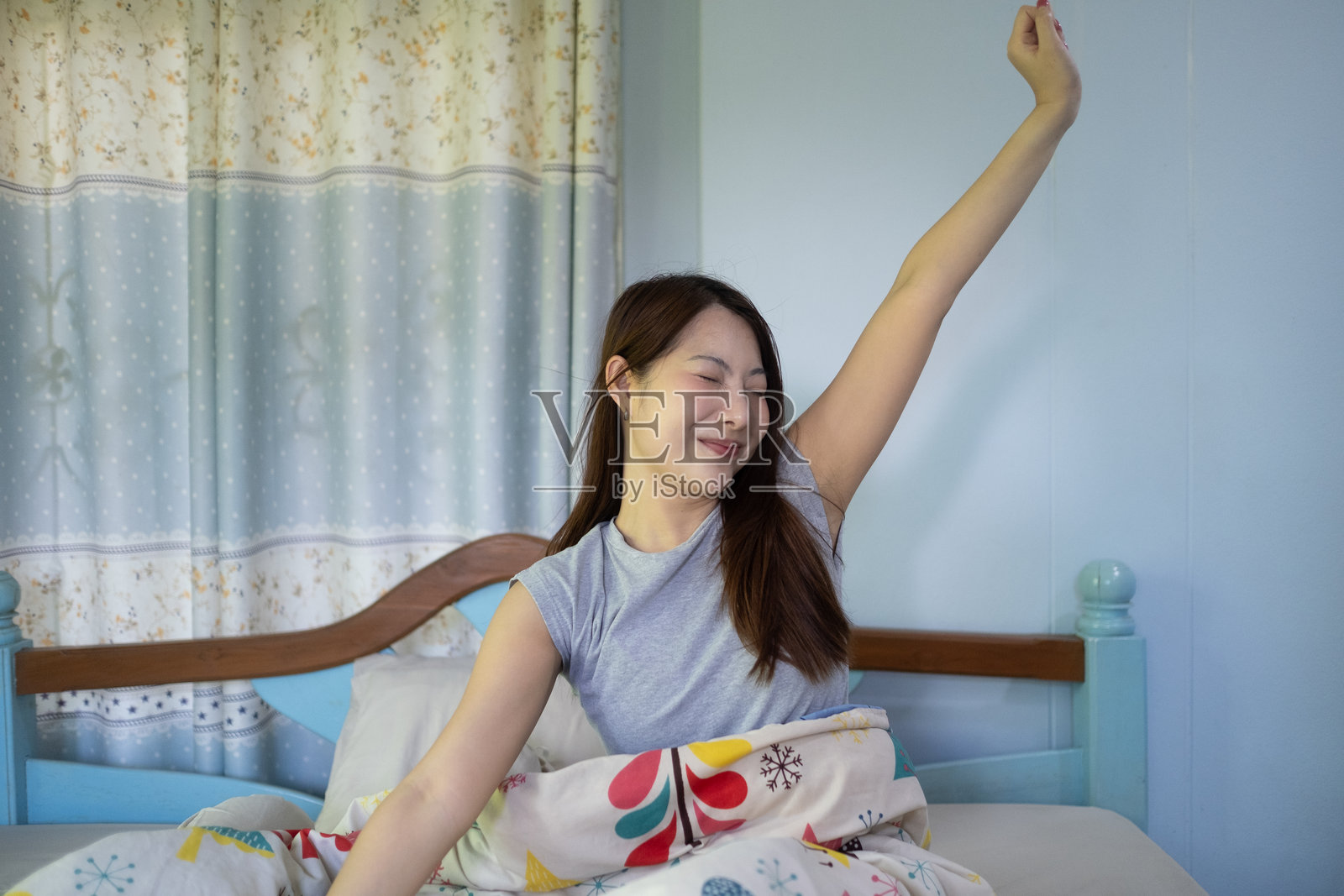 一个女人在床上伸懒腰,面带微笑照片摄影图片