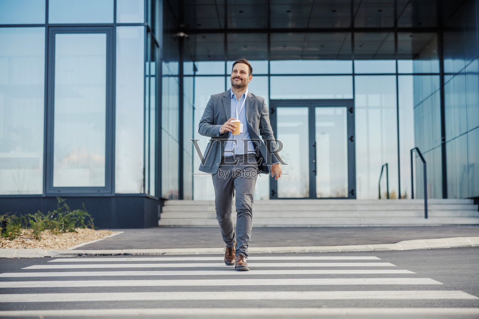 一位商务男士一手拿着咖啡,一边走回办公室照片摄影图片