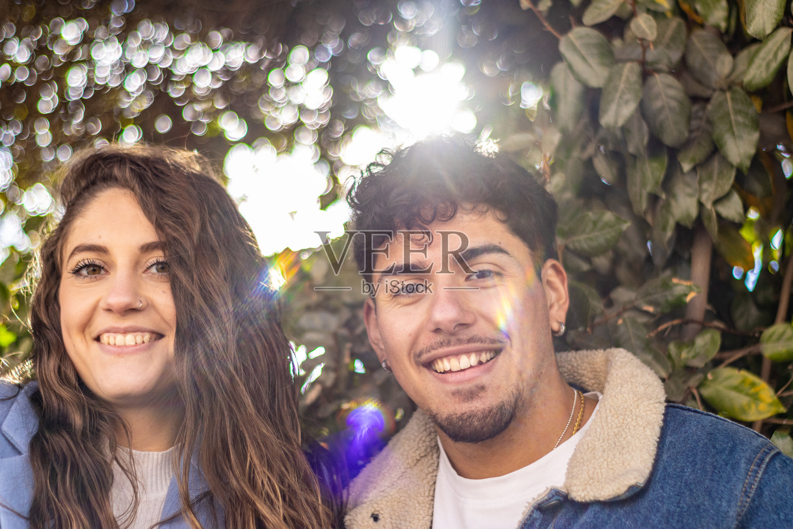 一对幸福的跨种族情侣在阳光和散景中对着镜头微笑照片摄影图片