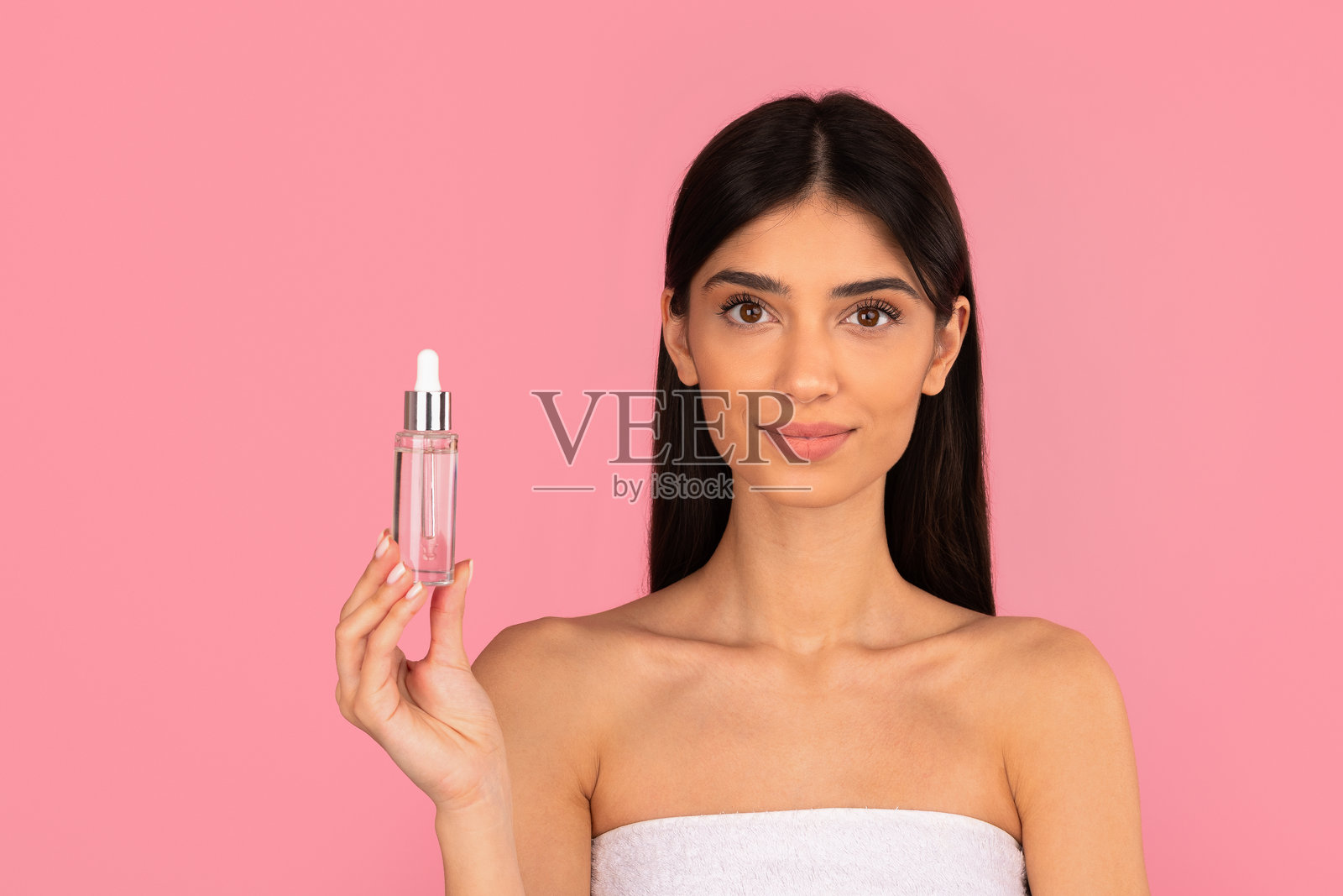 年轻美丽的女子,拥有洁净清爽的肌肤,手持一瓶精华液照片摄影图片