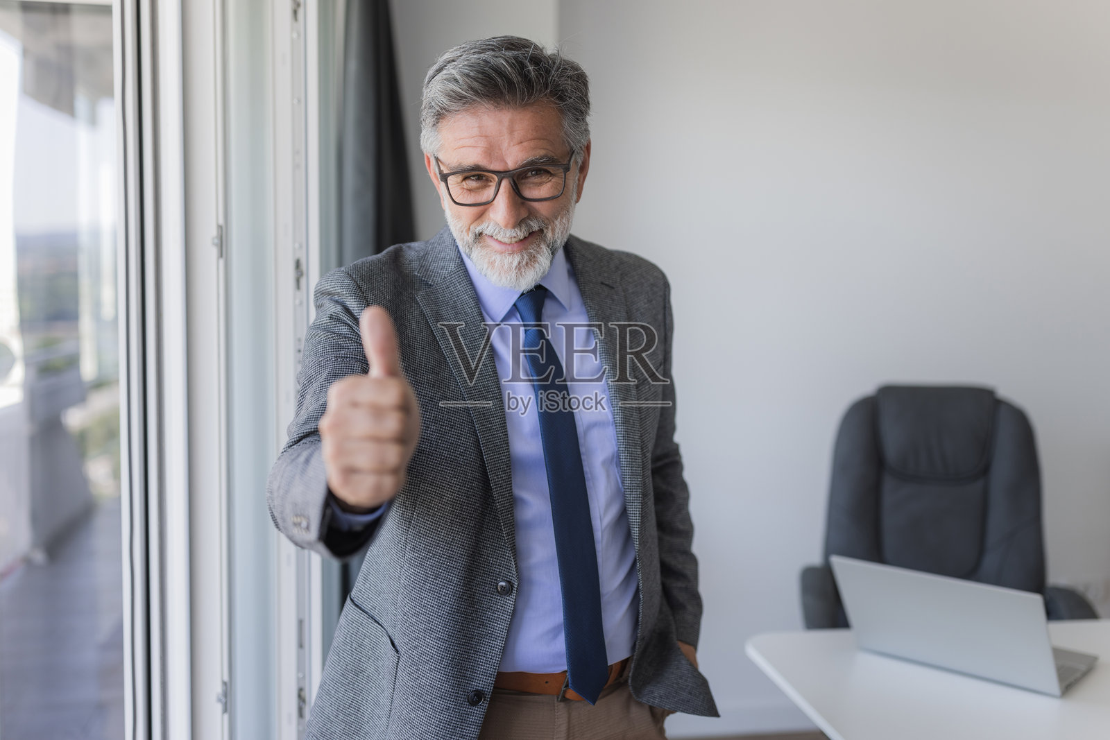 自信的商人微笑着在办公室里竖起大拇指照片摄影图片