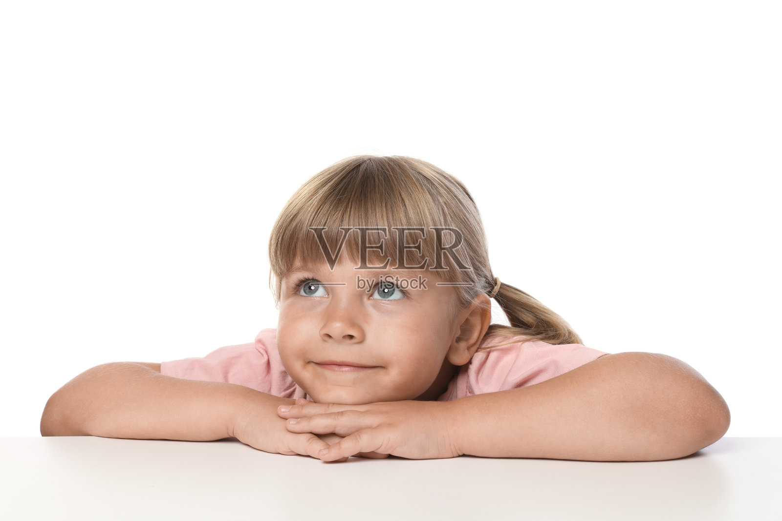 好奇的小女孩趴在桌子上,背景为白色照片摄影图片