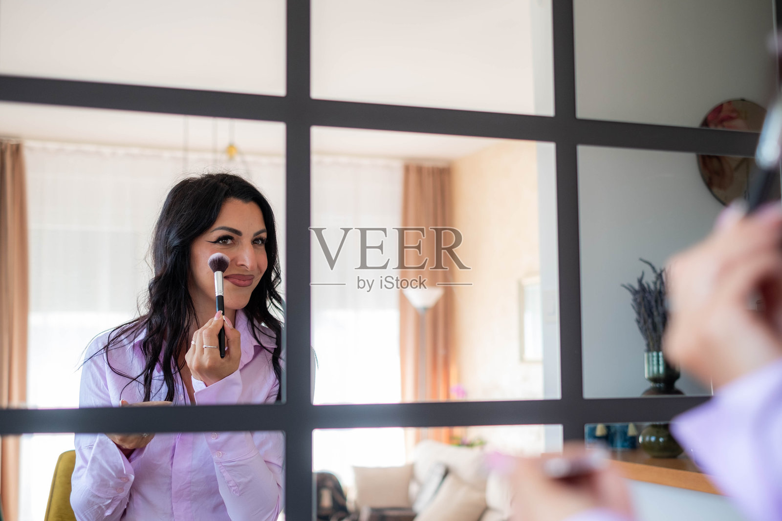 女人在镜子中映照出自己用刷子化妆的画面照片摄影图片